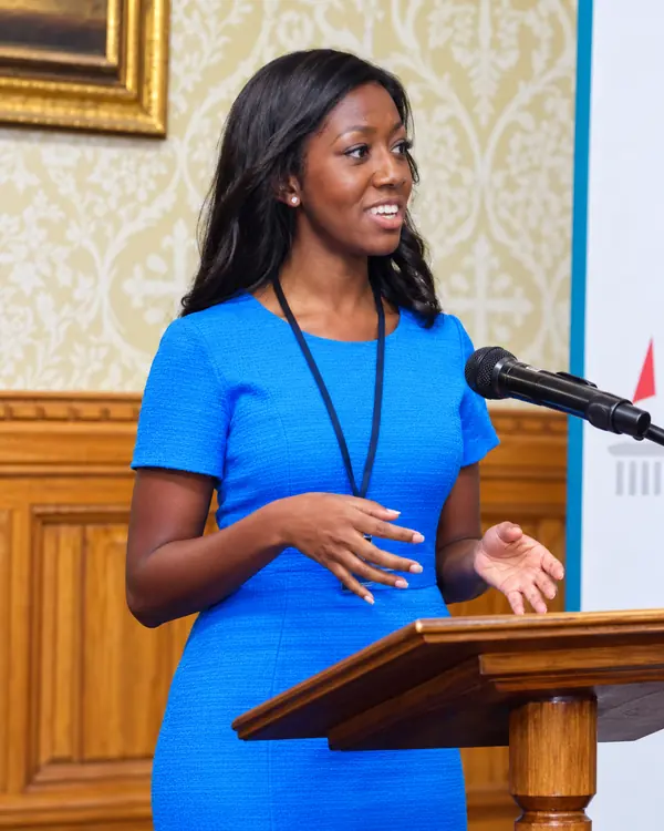 Speaker in a blue dress presenting at a lectern