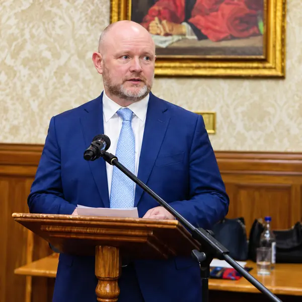 Speaker in a blue suit addressing the room